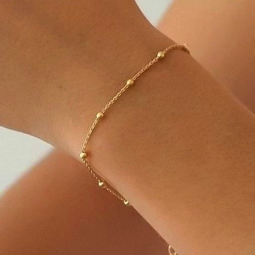 Filigrane Kette mit kleinen Goldkugeln, elegantes minimalistisches Design am Handgelenk