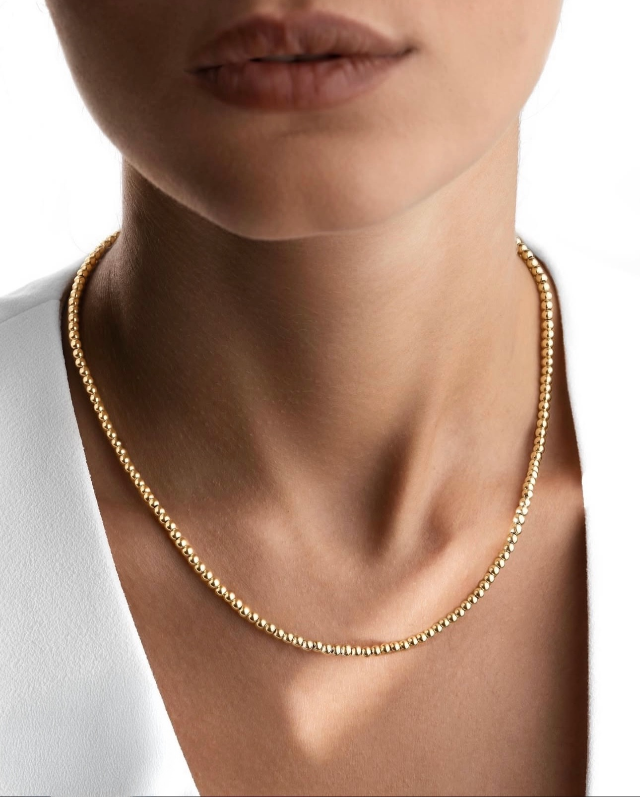 Goldene Perlenkette aus 18k â Morvarid-e Gardan, elegant am Hals getragen, zart glĂ€nzend zur weissen Bluse