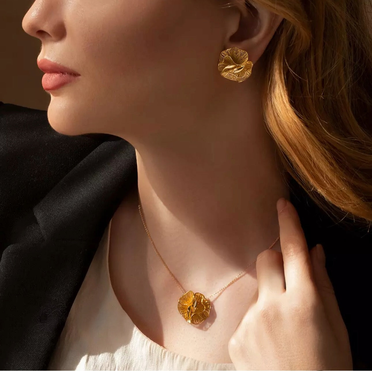 Tragebild einer Frau mit 18k Goldkette ‚Gol-e Shans‘ – floraler Anhänger in Blütenform, kombiniert mit passendem Ohrschmuck, stilvoll inszeniert bei natürlichem Licht