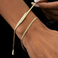 Goldarmband Khat-e Bâfteh aus 18k Gelbgold mit flach geflochtener Struktur – getragen am Handgelenk, elegant kombiniert mit feiner Kette