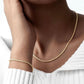 Ensemble aus 18k Gold im Kordeldesign – Halskette und Armband Tanab-e Tala, getragen in harmonischer Kombination auf heller Kleidung.