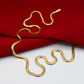 Feine Halskette aus 18k Gelbgold in eleganter Schlangenketten-Form, glänzend und geschmeidig auf rotem Stoff drapiert.