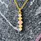 Detailaufnahme einer 18k Goldkette mit Anhänger aus roséfarbenem und weißen Zirkonia auf Marmorhintergrund.