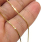 Nahaufnahme einer Venedig-Kette aus 18k Gelbgold, locker über die Finger einer Hand gelegt. Die feinen, quadratisch geschnittenen Glieder reflektieren das Licht gleichmäßig und erzeugen einen klaren, präzisen Glanz. Hintergrund neutral und unscharf.