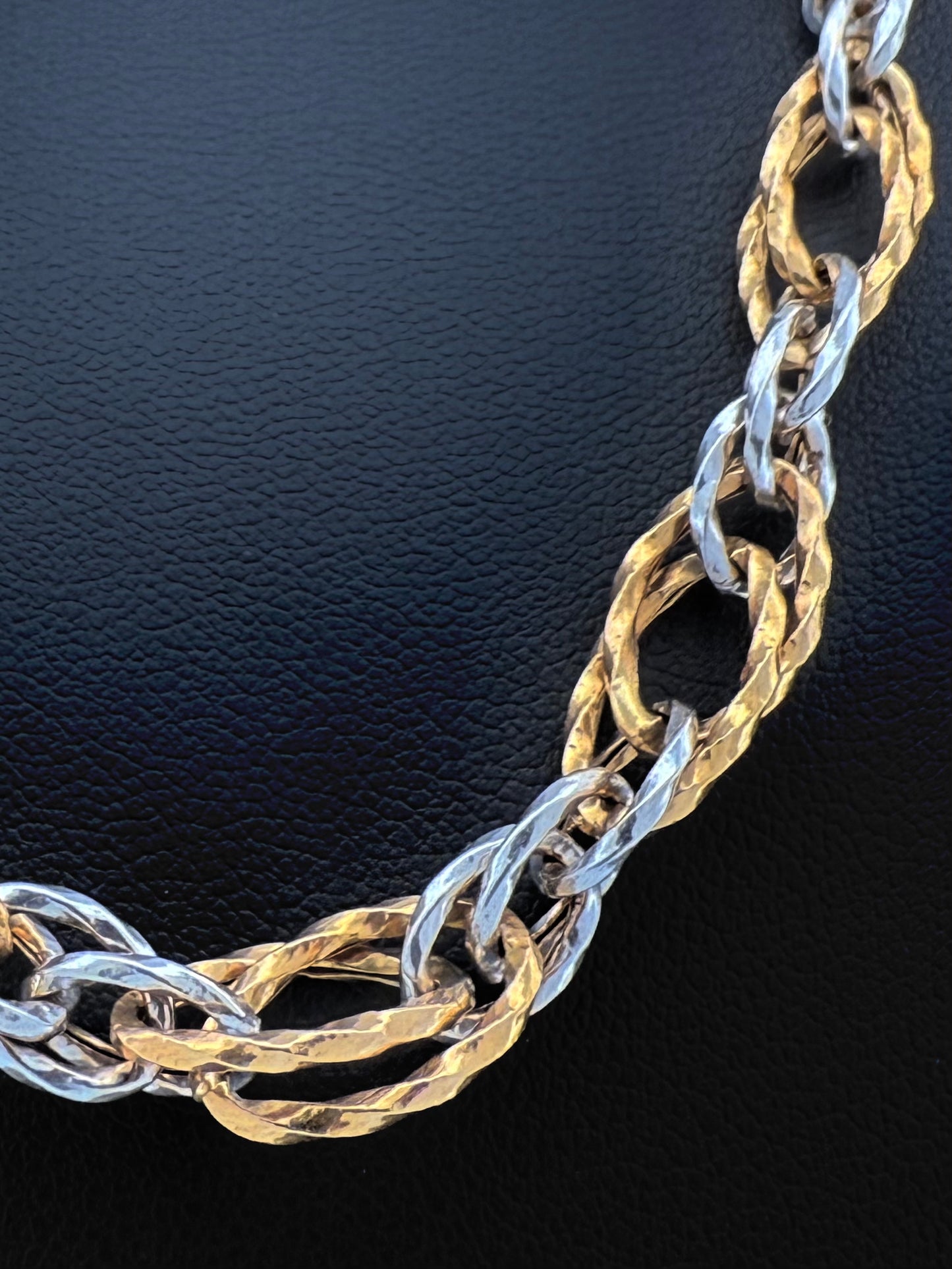 Grossaufnahme einer edlen Halskette aus 18k Gold in Gelb und Weiß mit gehämmerter Oberfläche. Persische Goldschmiedekunst in moderner Interpretation.
