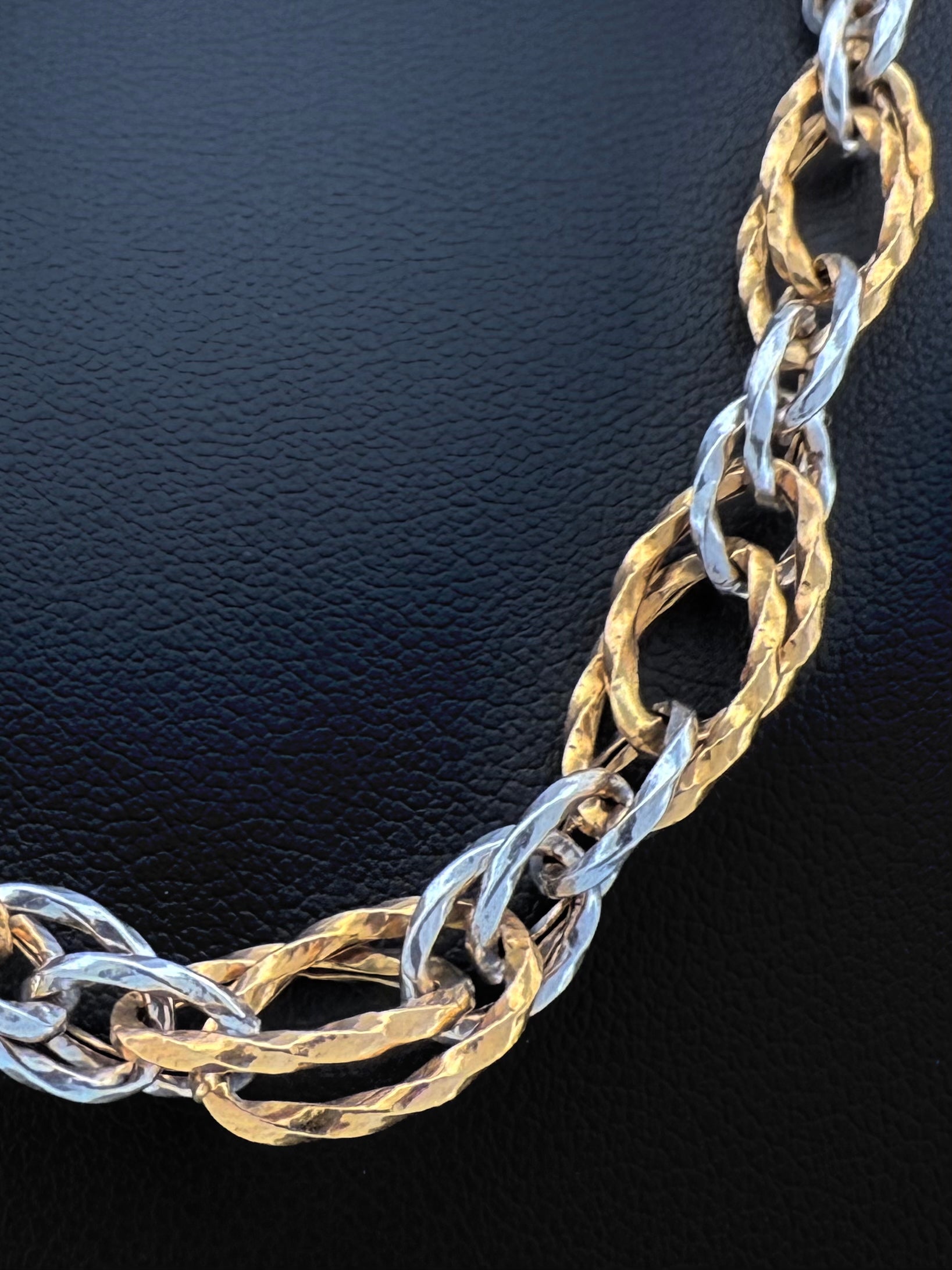 Grossaufnahme einer edlen Halskette aus 18k Gold in Gelb und Weiß mit gehämmerter Oberfläche. Persische Goldschmiedekunst in moderner Interpretation.