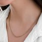 Nahaufnahme einer zweifarbigen Mirokette aus 18k Gelbgold und Weißgold, die locker um den Hals einer Frau liegt. Die feine, dicht verflochtene Gliederstruktur kombiniert warmen Goldton mit kühlem Silberglanz und erzeugt einen dezenten, eleganten Farbkontrast. Getragen zu einem weißen Oberteil mit offenem Kragen.