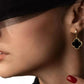Tragebild: Schwarze Onyxohrringe in Gold – elegant am Ohr getragen mit rotem Nagellack