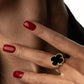 Goldring mit schwarzem Onyx-Kleeblatt auf Hand getragen – mit rotem Nagellack
